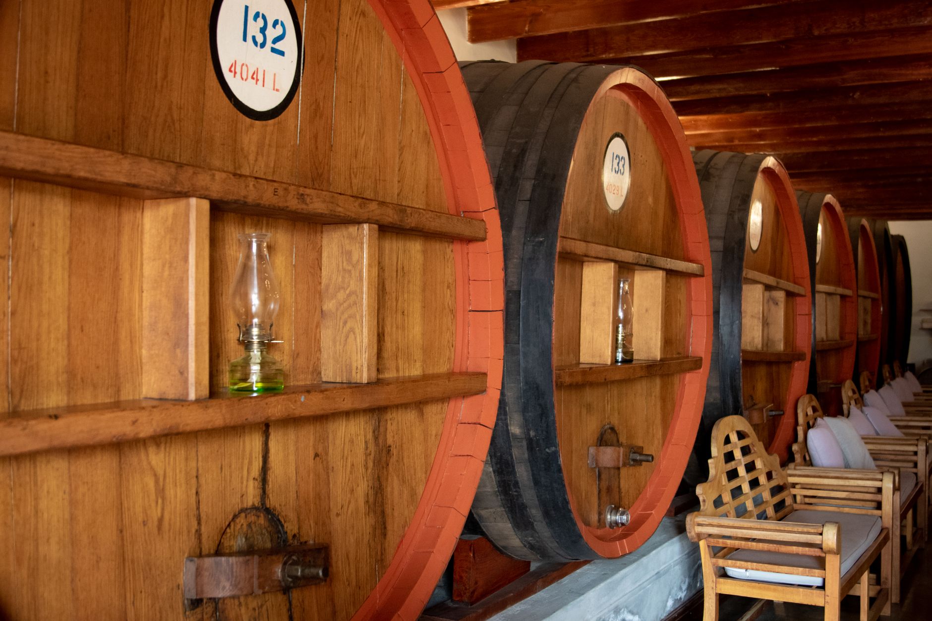 Cozy wine cellar interior featuring large wooden barrels and seating area.